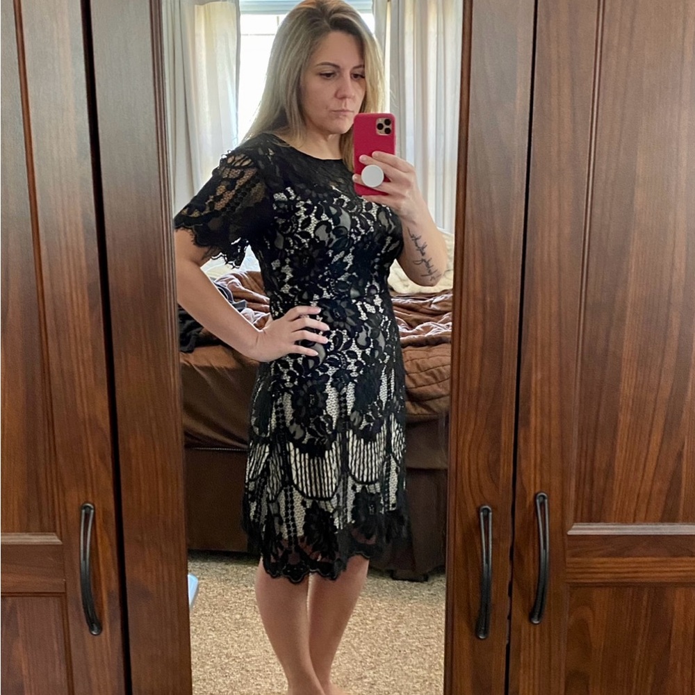 Women’s black lace dress over white/nude slip.